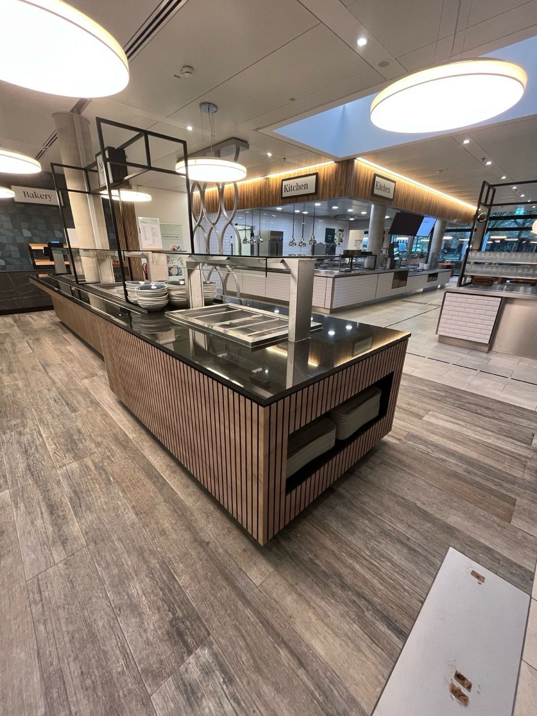 Buffet- und Ausgabecounter mit Lamellenfront und Steinplatte vor den Front-Cooking-Stationen
